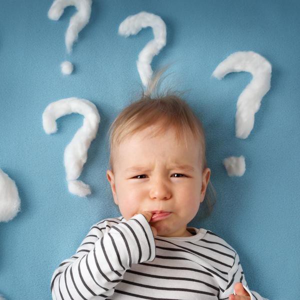 little boy lying on blue blanket with lots of question marks